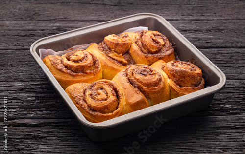 Delicious golden cinnamon rolls, fresh from the oven, presented on a metal tray with a homemade and appetizing look.