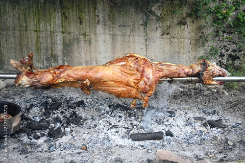 Whole lamb roasting on a spit over hot coals. A traditional Balkan culinary specialty. Succulent lamb meat turning on a spit above a wood fire.