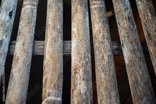 Perspective close up of weathered split bamboo slat texture with selective focus.
A high-quality close-up photograph capturing the rustic and organic texture of aged bamboo slats arranged in a paralle