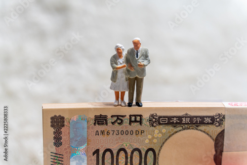 百万円の札束の上に立つ老夫婦
