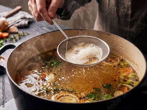 Skimming Delicate Foam from Simmering Artisanal Broth with Wire Mesh Ladle