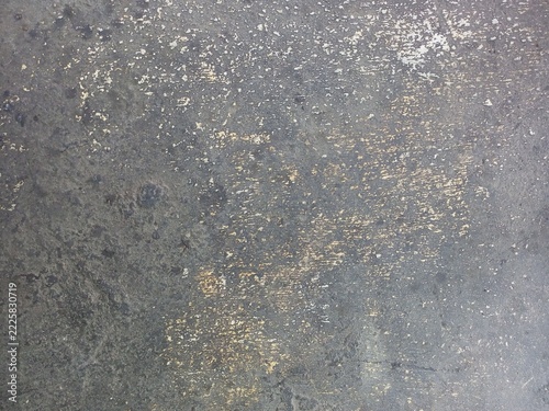 Weathered dark grey concrete floor with worn speckles