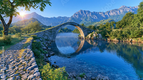 Stunning Stone Bridge Over Clear River Surrounded by Majestic Mountains at Sunrise