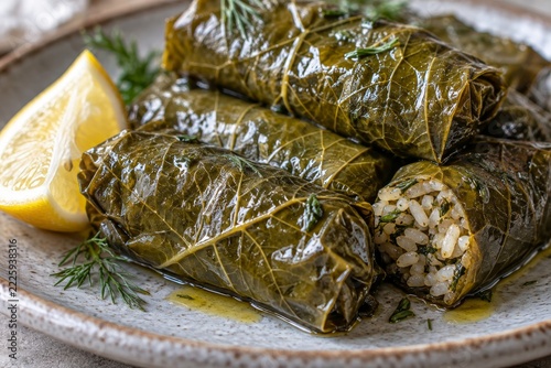 Turkish stuffed grape leaves with rice and lemon on a plate. Traditional dolma dish in close-up. Mediterranean cuisine and home cooking. Savory appetizer for a shared meal.