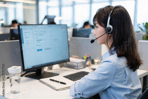 Female customer service agent working with headset in modern office environment