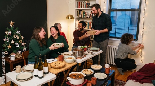 Diverse friends enjoying holiday dinner and gift exchange at home