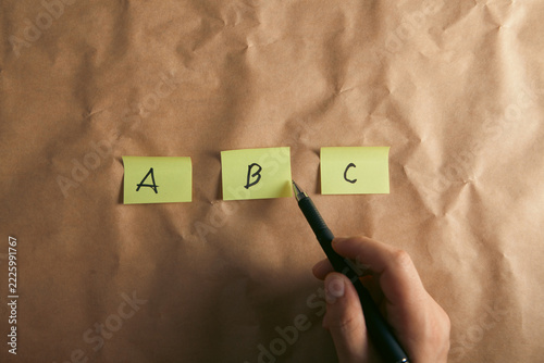 Hand writing ABC on sticky notes on crumpled paper, closeup