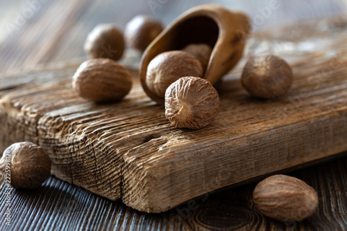 Whole nutmeg seeds scattered on rustic wooden surface with shell