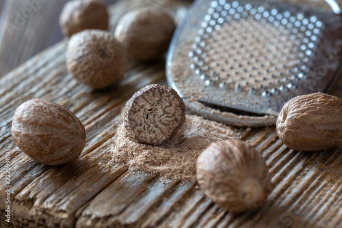 Whole nutmeg seeds and grated nutmeg on rustic wooden surface