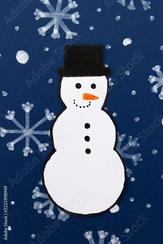 Paper snowman on a dark blue background with drawn snowflakes. Winter and Christmas concept for advertising, graphic compositions, and seasonal designs