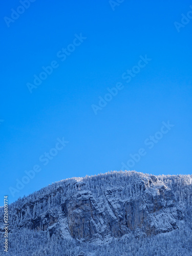 Snowy Mountain Cliffs With Vertical Blue Sky And Copy Space