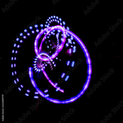 LED Poi Performer Spinning Purple and Blue Light Loops at Night