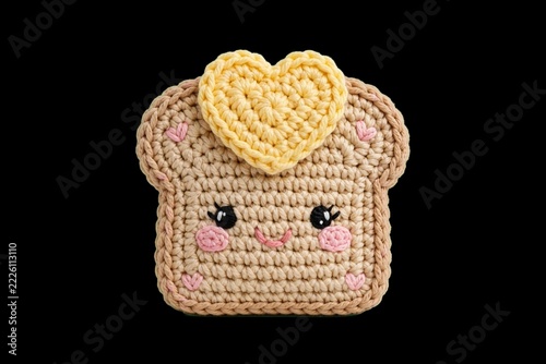 Handmade kawaii amigurumi crochet art of a smiling toast with a yellow butter heart, isolated on a solid black background. Adorable food character for nursery decor, Valentine's greeting, or breakfast
