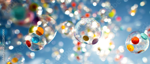 Colorful transparent glass spheres with suspended beads and sparkling highlights against a blue background, abstract decorative arrangement with shallow depth of field and bokeh