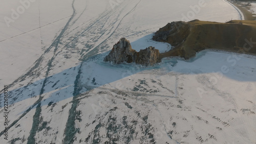 Fotografie Winter light falls across Shamanka Rock and the frozen shore near Khuzhir on Olk