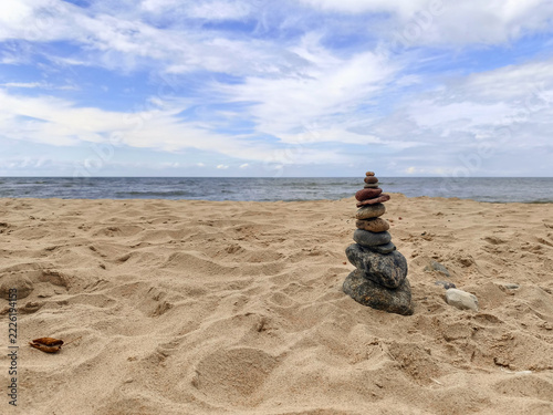 Stacked Stones Cairn on Sandy Beach by the Sea with Blue Sky, Zen Balance and Tranquility