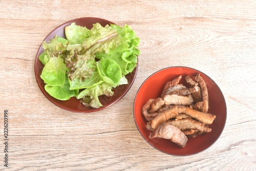 fried slice salty beef meat in bowl with mixed vegetable salad on plate 