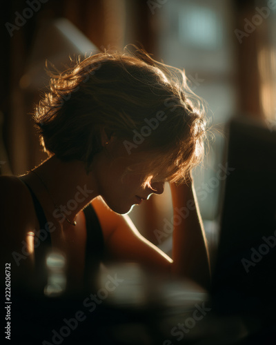 Young woman working on a laptop computer with backlight and cinematic lighting