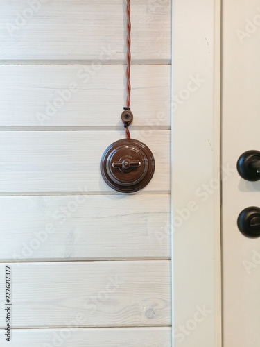 Closed door and vintage light switch on a white wooden wall