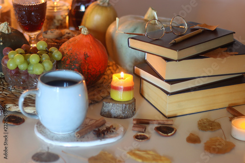 Table filled with pumpkins, candles, drinks, snacks and books. Autumnal hygge, selective focus.