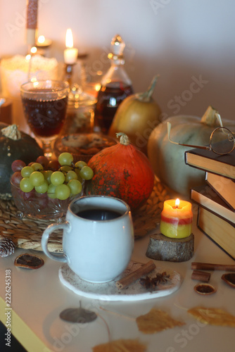 Table filled with pumpkins, candles, drinks, snacks and books. Autumnal hygge, selective focus.
