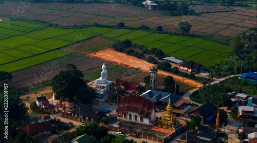 Fotografie Aerial view white seated buddha statue beside temple and rice paddy fields in Chiang Rai Thailand