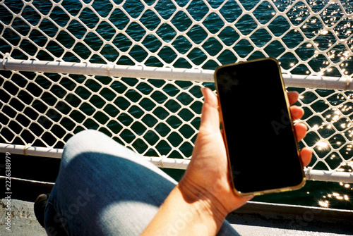 POV view of woman holding mobile phone while traveling on ferry boat