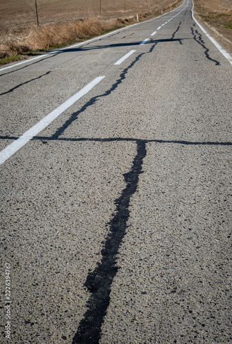 Cracks and breaks in the old, worn asphalt road have been repaired with melted bitumen. Asphalt road maintenance and repair. Repaired asphalt road.