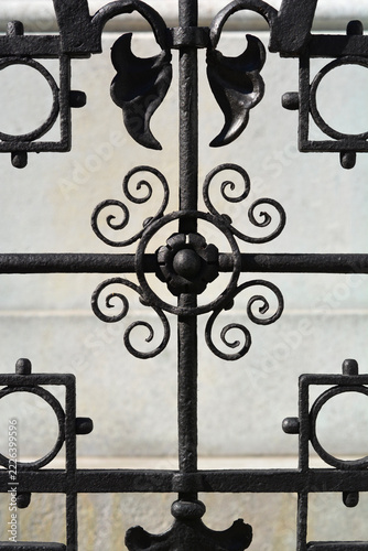 Obraz na plátně A close up shot of a classic black painted wrought iron fence featuring a symmetric geometric pattern with decorative scrollwork elements and flower motifs