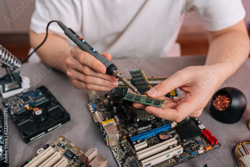 Close-up of technician repairing electronic component. Engineer soldering computer memory chip with precision tool. Technology maintenance, hardware upgrade workshop service concept.
