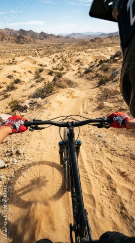 Point of view shot of mountain biking on a desert dirt trail, sunny arid landscape with hills.