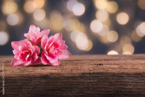 Stockfotografie rosa Blüten auf Holz mit Bokeh-Lichtern