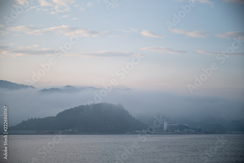 Thick morning fog flowing over mountains and sea at dawn in June