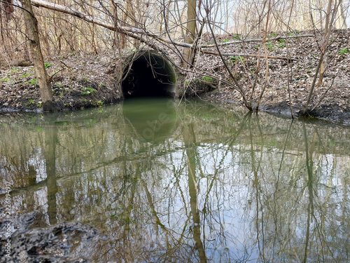 Large-diameter reinforced concrete pipe under forest dirt road for water drainage. Large reinforced concrete pipe installed under dirt road to prevent washout