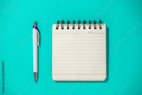 notepad and pen on blue background, top view