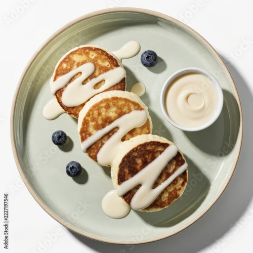 Realistic textures of pan fried cottage cheese pancakes with condensed milk ribbons on pure white background — studio lighting editorial food photo for gourmet breakfast and comfort food