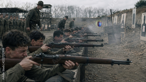 Soldiers practice marksmanship at an outdoor firing range, conveying military instruction, discipline, coordinated preparation and the development of rifle skills before active frontline service.