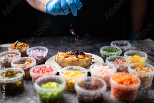 Baked potatoes with cheese, herbs, meat and butter. Copy space background. BBQ or steakhouse side dish favorite with tomato beans, cheddar cheese, bacon.