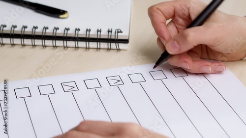 Close-up of a person marking checkboxes on a checklist with a black pen on a wooden desk. Planning, goal achievement, and task management concept.