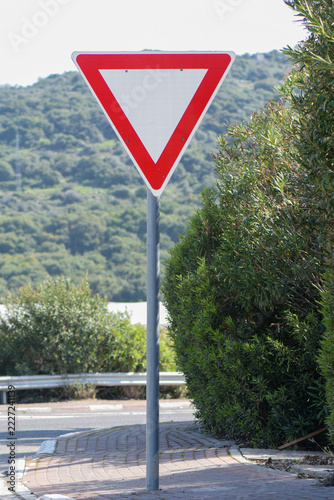 Yield Traffic Sign Near Curved Road With Green Hills in Background