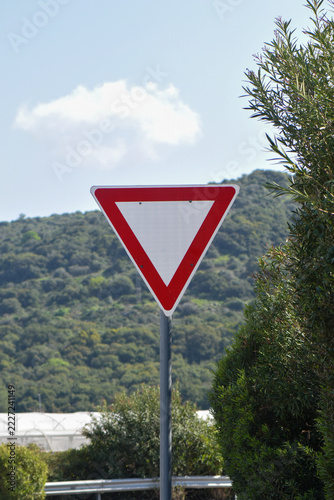 Yield Traffic Sign Near Curved Road With Green Hills in Background
