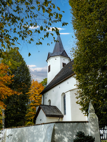 White Church With Steeple Surrounded by Autumn Trees and Blue Sky in Peaceful Setting
