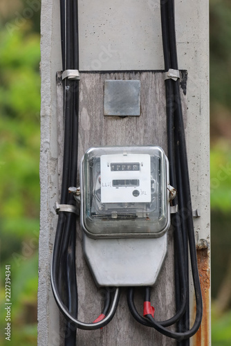 Analog Electricity Meter Mounted on Concrete Pole with Black Power Cables, Household Energy Consumption Concept