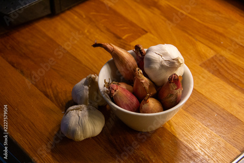Bowl of shallots and garlic bulbs on a wooden kitchen counter