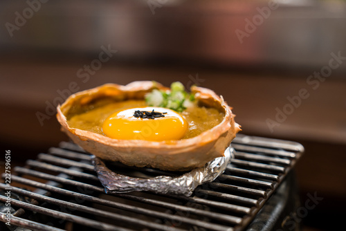 Fotografie Kani Miso, crab miso in shell bowl topped with elevated premium toppings with egg yolk, black sesame, bowl and sliced ​​scallions