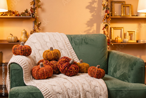 Cozy living room with knitted pumpkins on a green couch during autumn
