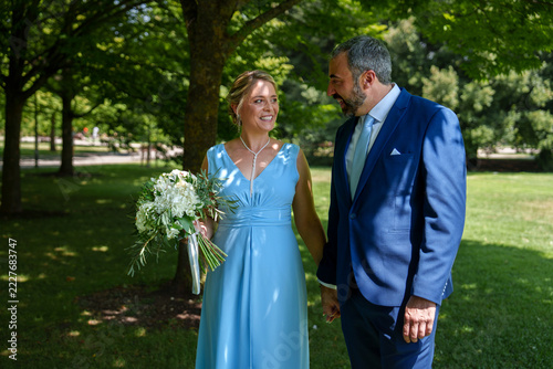 Civil wedding couple with bouquet in a sunny park