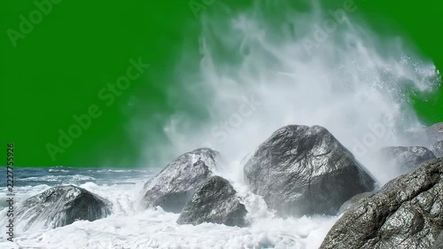 Ocean waves crashing against dark wet rocks on green screen background with white spray and foam, dynamic coastal storm footage.