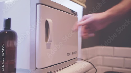 Hot towel warmer closeup. Barber hand opening door taking white cloth salon.
