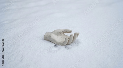 A lone hand emerges from the snow, a symbol of cold and isolation.